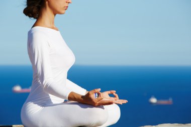 Cropped image portrait of young brunette woman practice yoga on high altitude with sea view on background, engage meditation