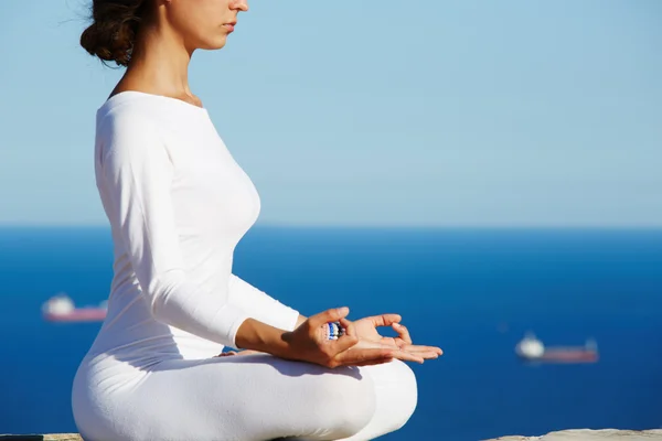 Cropped image portrait of young brunette woman practice yoga on high altitude with sea view on background, engage meditation — ストック写真