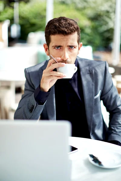 Serious and confident man drinking coffee sitting in cafe — Stock Photo, Image