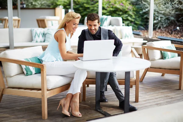 Business team of two successful people sitting outdoors in lounge terrace and planning work, businessman and businesswoman meeting in modern cafe, business partners having working with computer — Stock Photo, Image