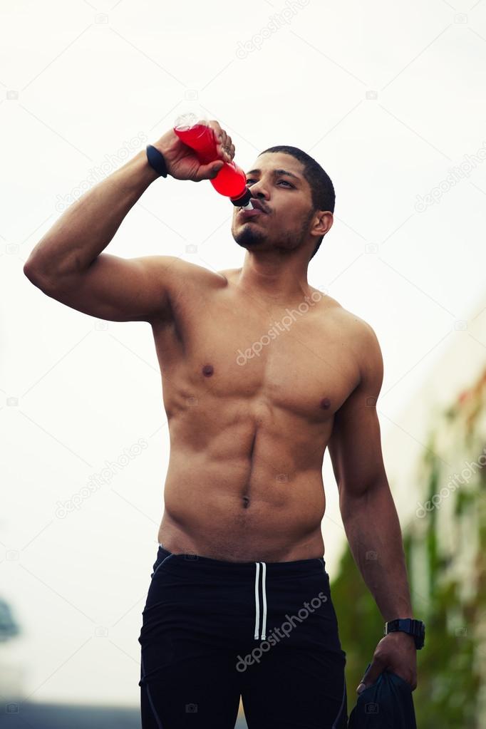 Half length portrait of athletic build dark skinned sportsman refreshing  with water after run outdoors Stock Photo by ©GaudiLab 56639833