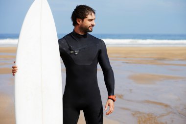Wetsuit sörf büyük dalgalar, mutlu sörfçü holding onun yönetim kurulu güneşli yaz gününde hazır üzerinde okyanus plaj, profesyonel sörfçü adam ayakta beyaz surfboard ile hipster adam portresi giymiş