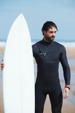Wetsuit sörf büyük dalgalar, mutlu sörfçü holding onun yönetim kurulu güneşli yaz gününde hazır üzerinde okyanus plaj, profesyonel sörfçü adam ayakta beyaz surfboard ile hipster adam portresi giymiş