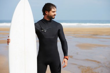 Wetsuit sörf büyük dalgalar, mutlu sörfçü holding onun yönetim kurulu güneşli yaz gününde hazır üzerinde okyanus plaj, profesyonel sörfçü adam ayakta beyaz surfboard ile hipster adam portresi giymiş