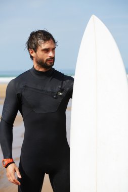 Wetsuit sörf büyük dalgalar, mutlu sörfçü holding onun yönetim kurulu güneşli yaz gününde hazır üzerinde okyanus plaj, profesyonel sörfçü adam ayakta beyaz surfboard ile hipster adam portresi giymiş