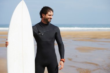 Wetsuit sörf büyük dalgalar, mutlu sörfçü holding onun yönetim kurulu güneşli yaz gününde hazır üzerinde okyanus plaj, profesyonel sörfçü adam ayakta beyaz surfboard ile hipster adam portresi giymiş