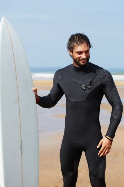 Wetsuit sörf büyük dalgalar, mutlu sörfçü holding onun yönetim kurulu güneşli yaz gününde hazır üzerinde okyanus plaj, profesyonel sörfçü adam ayakta beyaz surfboard ile hipster adam portresi giymiş