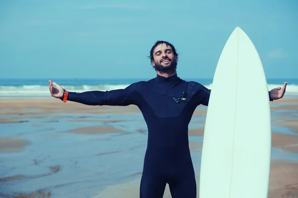 Unga surfare känsla så glad, attraktiv surfer njuter perfekt solig dag står på stranden och hålla med en hand hans surfingbräda, mår bra och nöjd med hälsosam livsstil, filtrerade bilden — Stockfoto