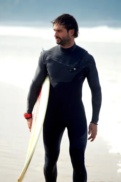 Attractive young surfer holding surfboard while standing on the beach looking at ocean to find the perfect spot to go surfing waves,professional surfer with surf board looking at ocean, filtered image — Stock Photo, Image