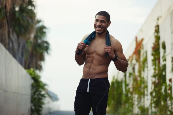 Cropped shot of attractive dark skinned male runner resting after self training outdoors — Stockfoto