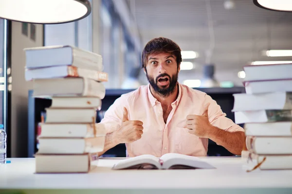 Jovem preocupado homem se preparando para seu exame final enquanto sentado na biblioteca da universidade — Fotografia de Stock