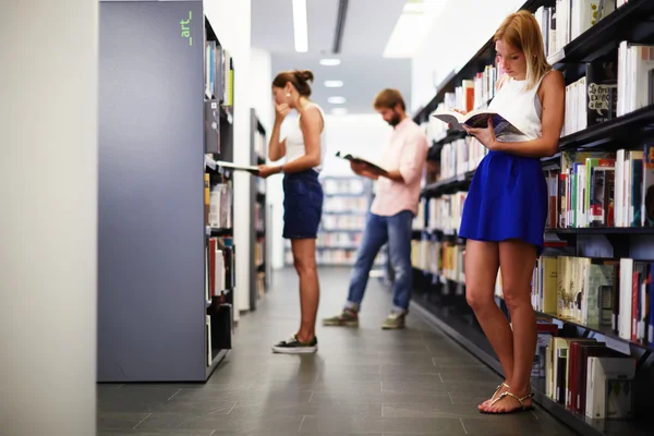 Grupo de estudantes internacionais à procura de alguns livros na biblioteca durante a preparação para exames — Fotografia de Stock