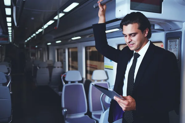Mature handsome businessman working with digital tablet during going to work in train — Stok fotoğraf