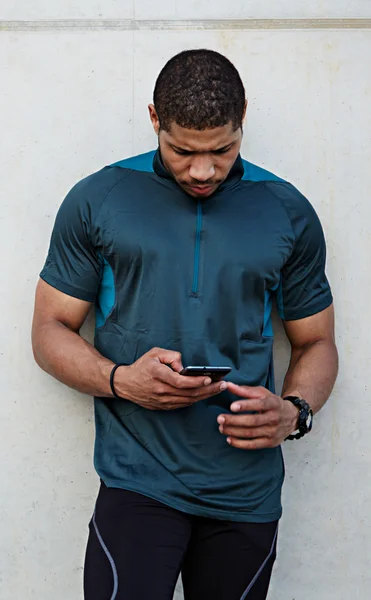 Fit man resting after workout outdoors holding mobile smartphone — Stock Photo, Image