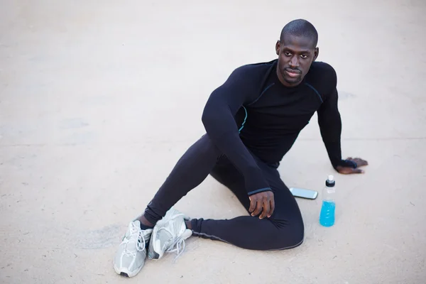 Smiling dark skinned runner resting after workout outdoors,male runner in active clothes taking break after run,active man having break after fitness training,confident sportsman looking to the camera — 图库照片