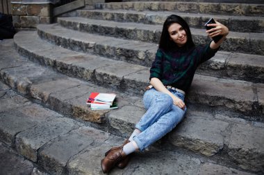 Young tourist girl taking a self portrait with smart phone in Barcelona, beautiful young hipster girl photographing herself with phone, young charming girl smiling while taking a self-ie outdoors