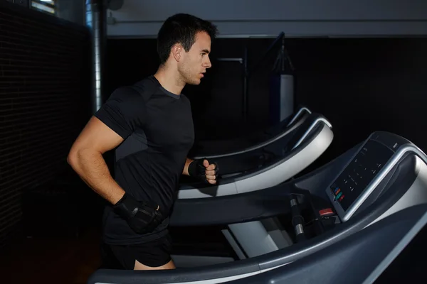 Fit man running in a gym on a treadmill looking to the screen, attractive sportsman at the gym doing exercise on the treadmill, handsome brunette man doing workout in gym running on treadmill — Zdjęcie stockowe