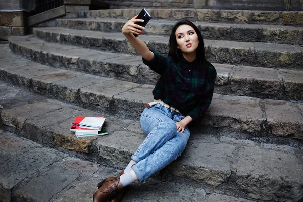 Pretty tourist girl taking a self portrait with smart phone in Barcelona, hipster girl photographing herself with phone, laughing student girl taking a self portrait with smart phone sitting on steps — Stock Photo, Image
