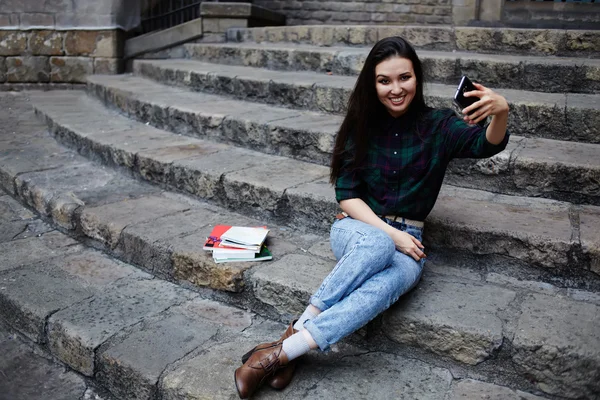 Menina encantadora jovem sorrindo ao tomar um auto-ie ao ar livre, jovem turista tomando um auto-retrato com telefone inteligente em Barcelona, bela jovem garota hipster fotografar-se com telefone — Fotografia de Stock
