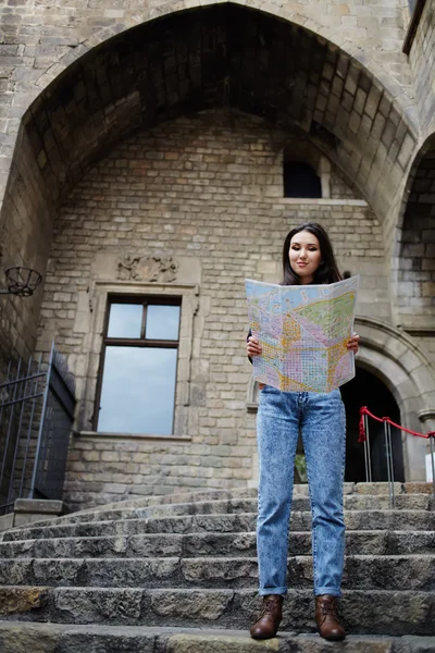 Beautiful tourist woman on vacation with a map in antique gothic city,young traveler girl searching right direction on city map, pretty young female tourist studying a map standing in gothic quarter