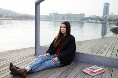 Barcelona bağlantı noktasının güzel manzarayı ahşap iskele üzerinde oturan çekici genç turist kız