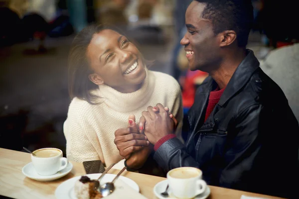 Laughing young couple in cafe, having a great time together, view through cafe window, romantic couple having fun together, best friends smiling sitting in cafe, view through cafe window — Zdjęcie stockowe