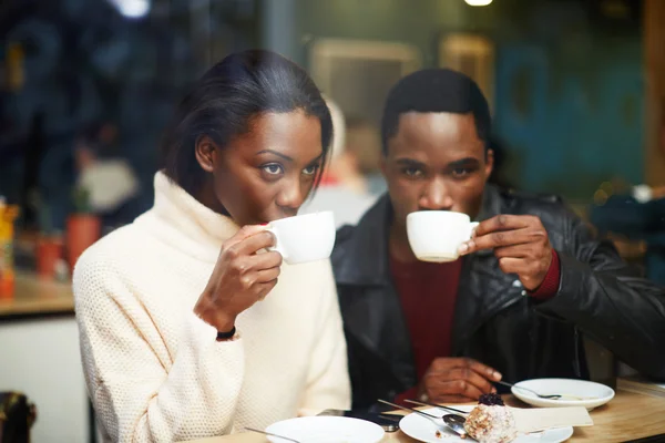 Friends enjoying coffee in beautiful place, cold winter days in beautiful coffee shop, friends at breakfast having coffee and enjoying themselves, two young friends holding cups drink coffee in cafe — Stok fotoğraf