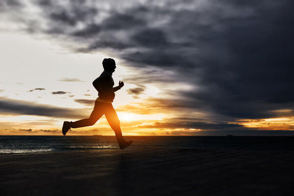 Man running towards gold sun