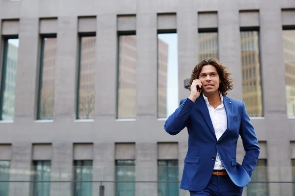 Empresário caminhando na cidade e falando ao telefone — Fotografia de Stock