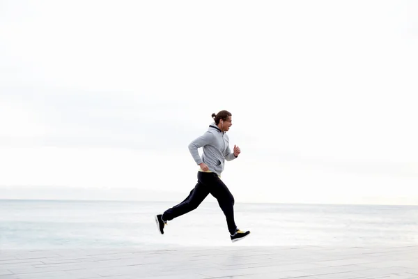 Νεαρός άνδρας που τρέχει κατά μήκος της παραλίας — Φωτογραφία Αρχείου