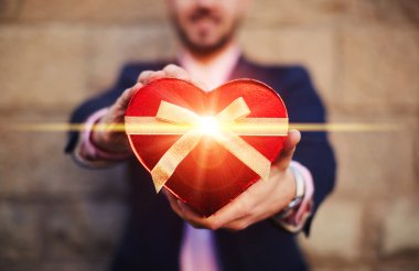 Bir kalp şekli hediye tutan adam