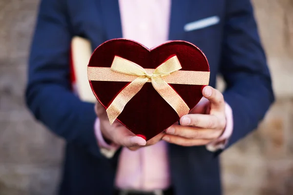 Hombre sosteniendo un regalo en forma de corazón —  Fotos de Stock