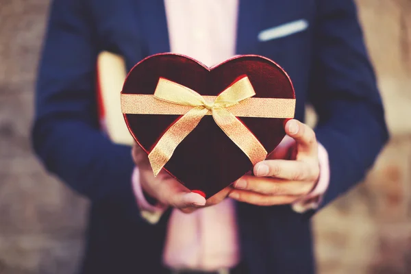 Uomo in possesso di un regalo a forma di cuore — Foto Stock