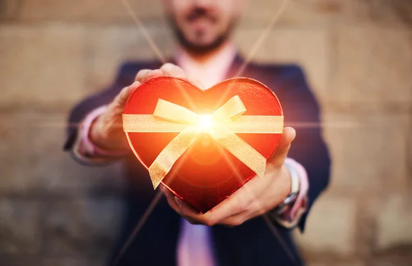 Uomo in possesso di un regalo a forma di cuore — Foto Stock