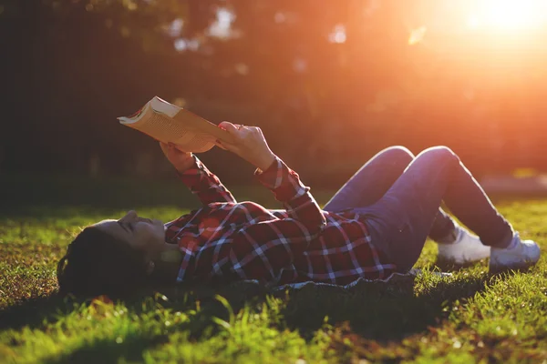 Mulher deitada na grama e lendo um livro — Fotografia de Stock