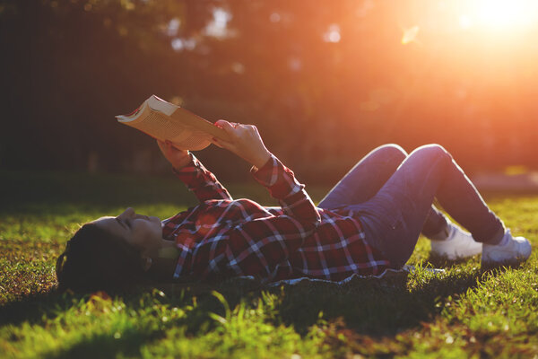 Woman lying on the grass and reading a book