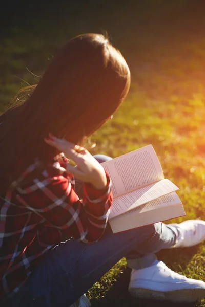 Une fille s'assoit sur une journée ensoleillée sur la pelouse et lit votre livre préféré — Photo