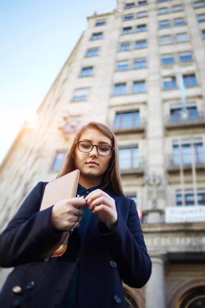 А woman with glasses standing in the city with digital tablet in the hand — Stockfoto