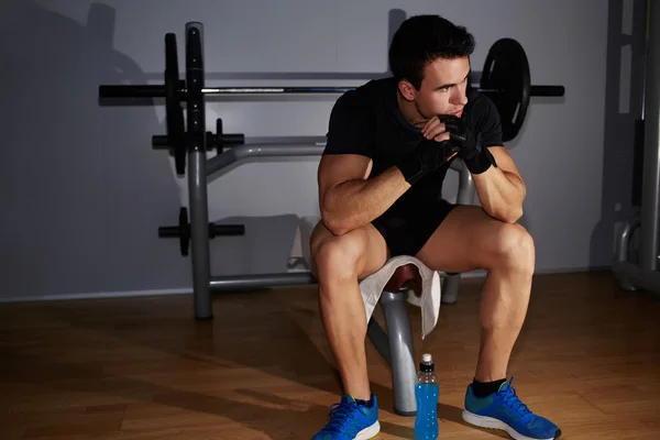 Man sitting against dumbbells equipment — Stock Photo, Image