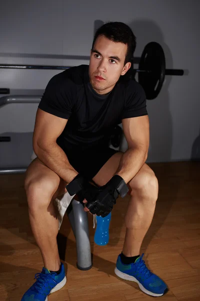 Culturista seduto su attrezzature da palestra — Foto Stock