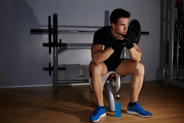 Atleta sentado en el equipo de gimnasio —  Fotos de Stock