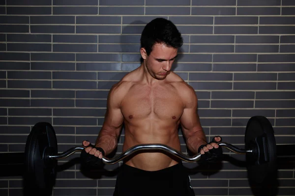 Muscular build athlete lifting barbell — Stock Photo, Image