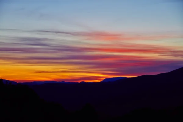 Pôr do sol sobre montanhas escuras — Fotografia de Stock