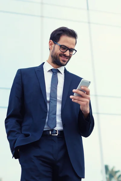 Empresário sorrindo enquanto lê uma mensagem de texto — Fotografia de Stock