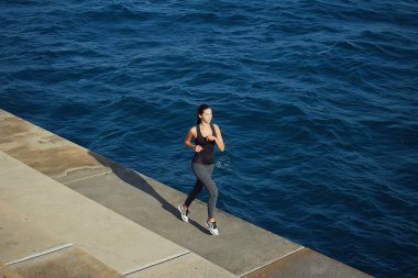 young woman running along the cement pier
