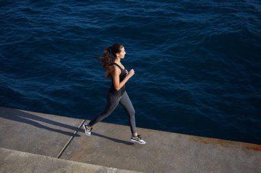 young woman running along the cement pier