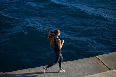 female runner jogging next to the ocean