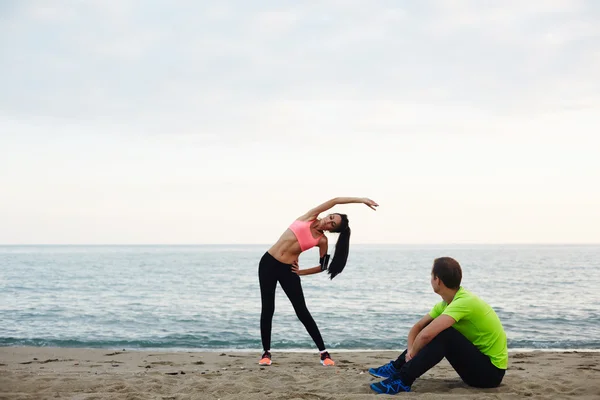 Аthletic man taking a break while his girlfriend exercising — Φωτογραφία Αρχείου