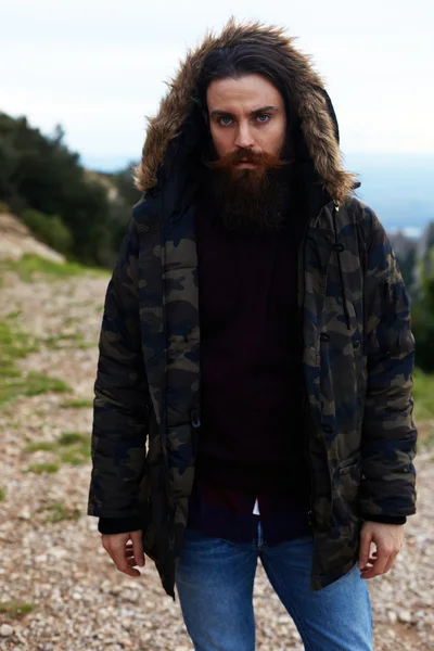 Man standing on top of a hill it warm jacket and draped over the hood — Stock Photo, Image