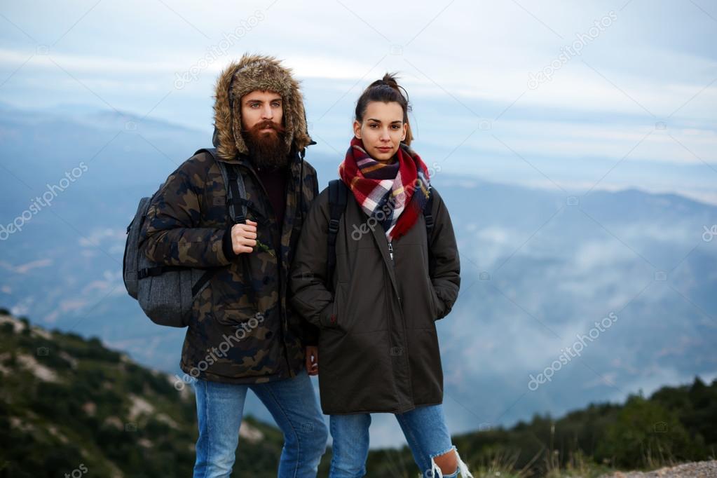 Backpackers standing on top of a mountain against foggy valley